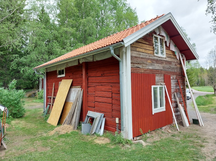 Ny panel på timmerhusets gavel – liggande på övervåningen, stående nedanför.